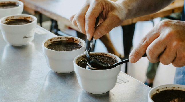 Inimene segab cupping’u käigus kohvitassides kohvipuru - kohvi degusteerimise oluline samm, kus avanevad joogiaroomid.