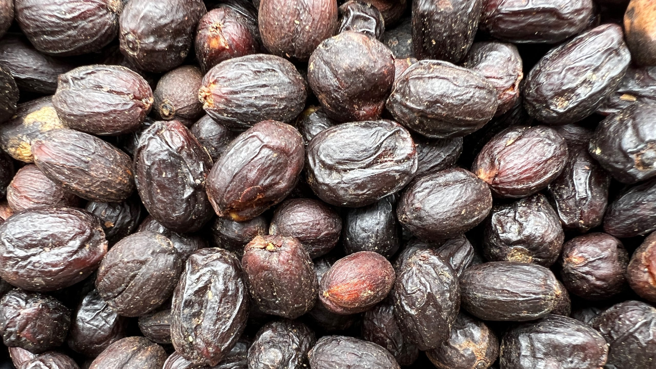 Close-up of dried coffee cherries from the natural processing method. The dark, wrinkled cherries have been dried with the fruit intact before the beans are removed.